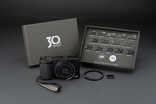 RICOH GR IV 30th Anniversary Edition Kit: fotocamera, confezione 30th Anniversary, 16 spille, cinturino in pelle, copriobiettivo ad anello e copri slitta